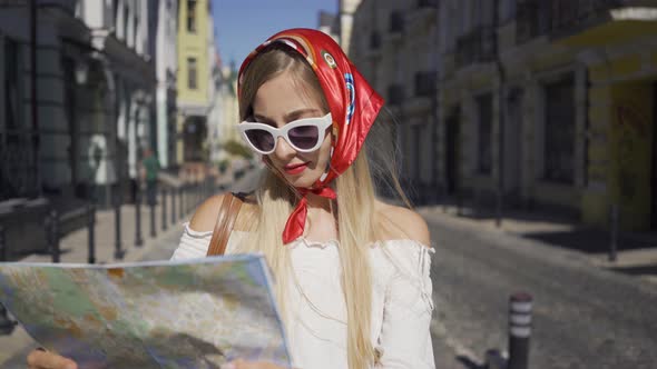 Positive Beautiful Young Woman Standing on the Street with the Map in Hands