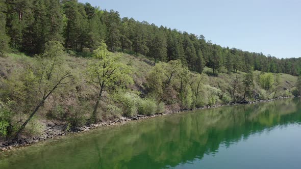 Aerial View; Drone Moving Along the Rocky Coast of Mountain Lake