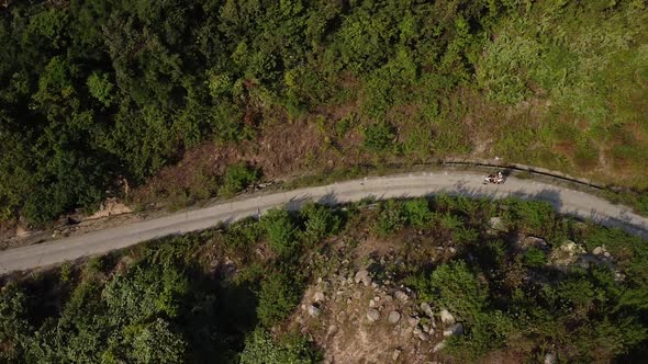 Aerial View of Tourist on Motorbike Driving Along a Curvy Road in the Mountain.