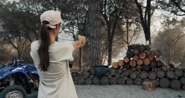Young Brunette Woman Successfully Shoots Tin Cans From Air Revolver in Forest
