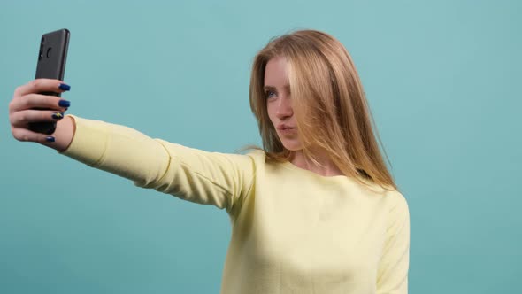 Young Blonde Haired Woman Making Selfie on Turquoise Background