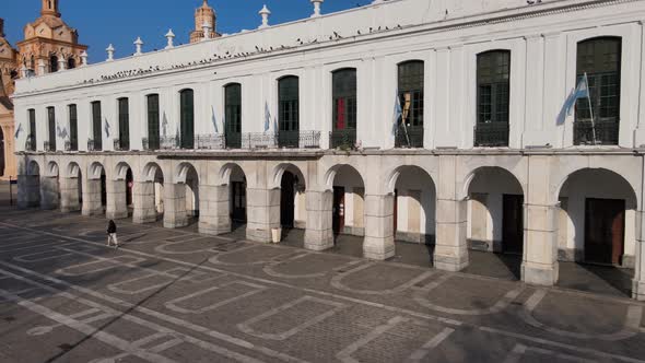 Aerial pan shot capturing quiet square and Cordoba Cabildo colonial town hall with iconic arch passa