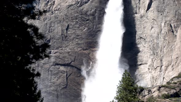 Yosemite falls upper to lower view from behind trees, Tilt down reveal shot