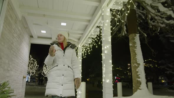 Woman Drinks Tea a Cup While Walking By Terrace at Town Village on Winter Night