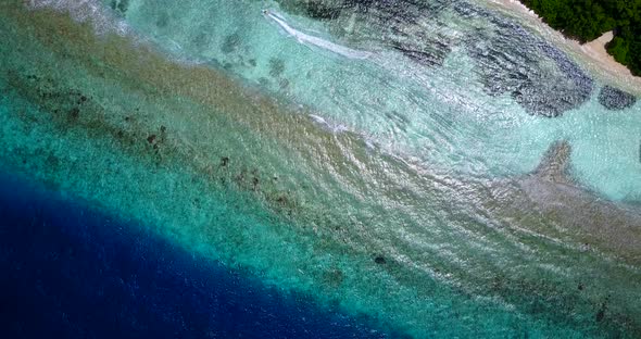 Wide angle flying tourism shot of a sandy white paradise beach and blue ocean background in hi res 