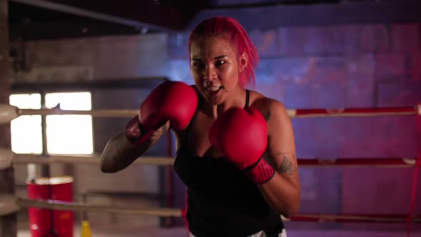 Young sporty woman doing boxing training inside a boxing ring.