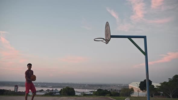 Young Boy Playing Basketball Alone on Court