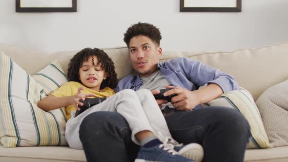 Happy biracial man and his son playing video games