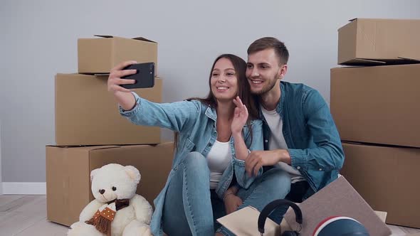 Happy Couple which Photographing on Phone while Sitting on the Parquet in their Just Bought Flat