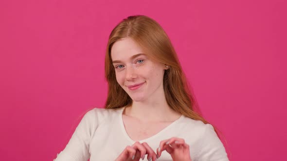 Close Up of a Happy Woman with Freckles That Make with Fingers Heart Shape