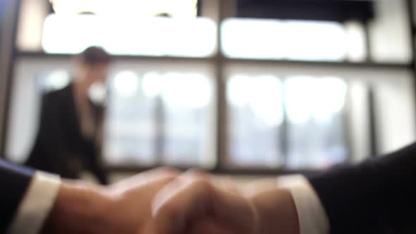 Secretary Working with Papers while Businessmen Shaking Hands