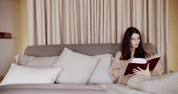 Woman Reading a Book Lying on Bed at Home