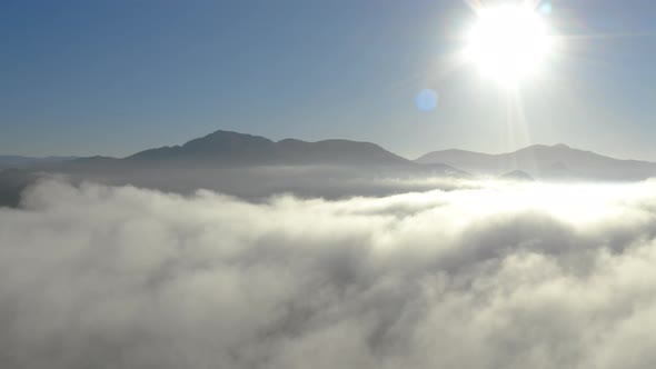 Aerial view of low fog over mountains in San Diego during sunrise