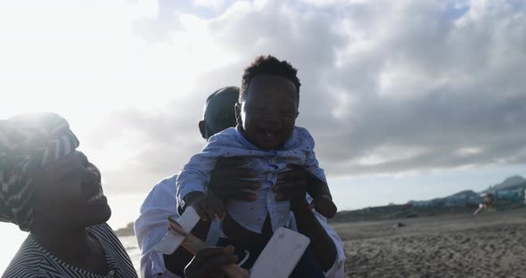 African parents and cute little son having fun on the beach at sunset - Family people and love