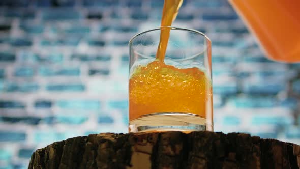 Pour Yellow Lemonade Into A Glass On A Brick Wall Background. Orange Juice.