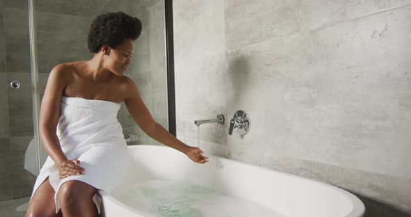 Happy african american woman preparing bath in bathroom