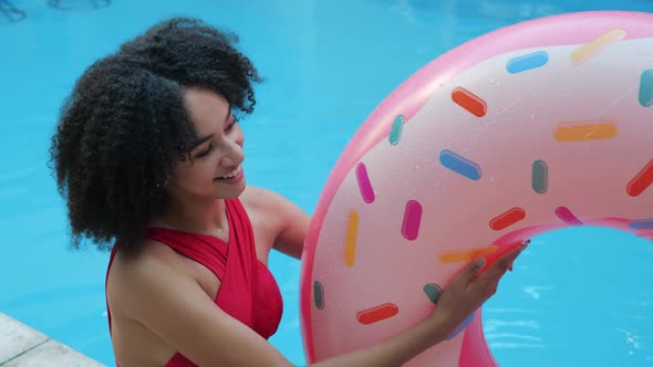 Close Up View of Playful African Model Play Throw Up Inflatable Donut in Mid-air Laughing Looking at