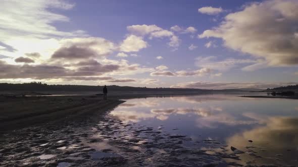 Unrecognizable person standing near water in cloudy evening