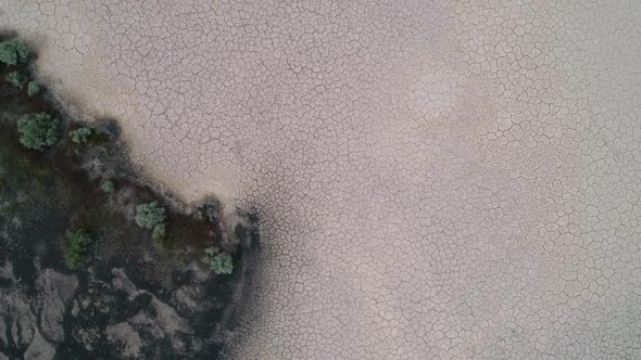 Flying over dry desert past person standing in cracked sand