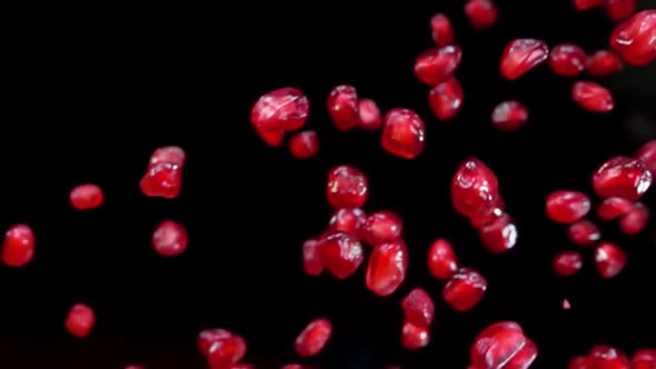 Juicy Pomegranate Grains Are Flying Diagonally on the Black Background 