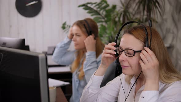 Closeup of Two Women Putting on a Headset in the Office Before Starting Work