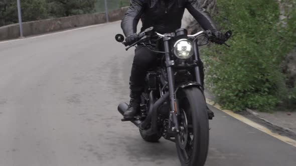 Biker on Motorcycle Rides on an Asphalt Road in the Middle of the Forest