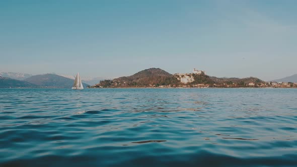 Teal colored Low-angle surface level view of small boat sailing on Maggiore lake. Italy