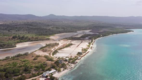 Salt pans along coast near Playa Ensenada with mountains in background, Dominican Republic. Aerial d