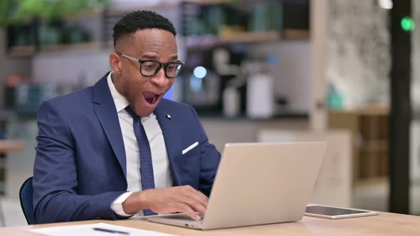 Excited African Businessman Celebrating Success on Laptop in Office 
