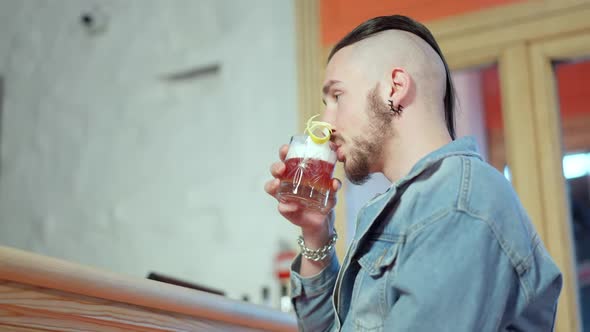 Young Millennial Man Drinking Cocktail Turning to Camera Toasting and Smiling