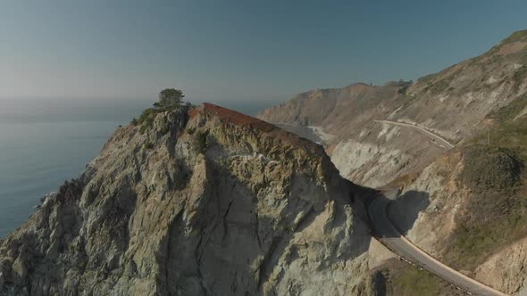 Aerial Push In of Tree on Rock on California Coast Highway One