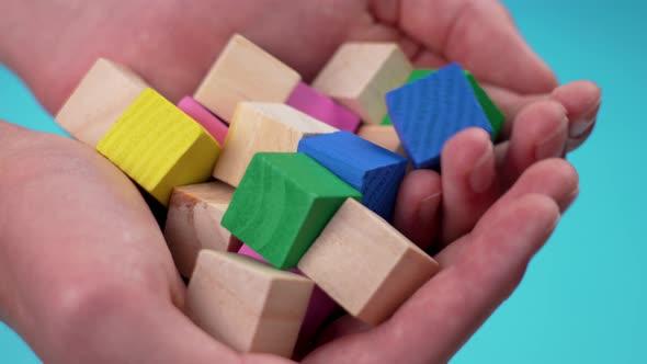 Educational wooden colorful toy blocks on blue background in hands. Game building cubes