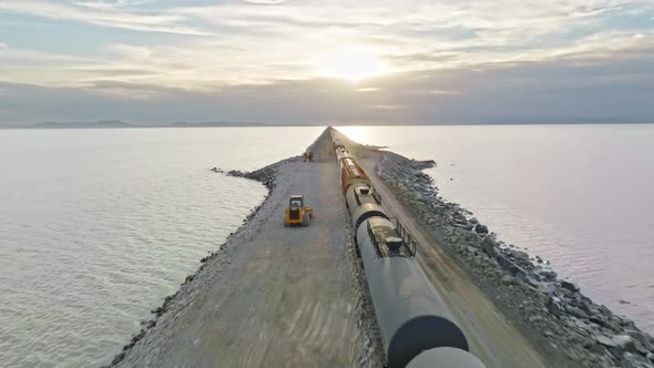 AERIAL - Train on railroad tracks at sunset, Great Salt Lake, Utah, tracking truck right