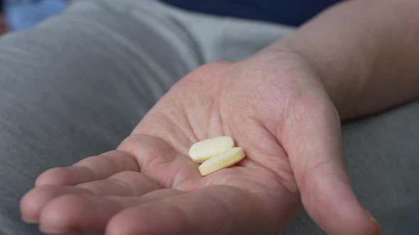 Two Yellow Tablets are Poured on the Palm of the Hand to Treat Serious Diseases