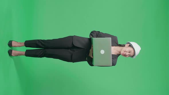 Full Body Of Asian Female Engineer Looking Around While Using Laptop In The Green Screen Studio