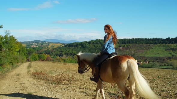 Young woman riding on horse through idyllic landscape