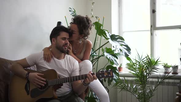 Man Learning to Play Guitar and His Wife or Girlfriend Listening Spbd