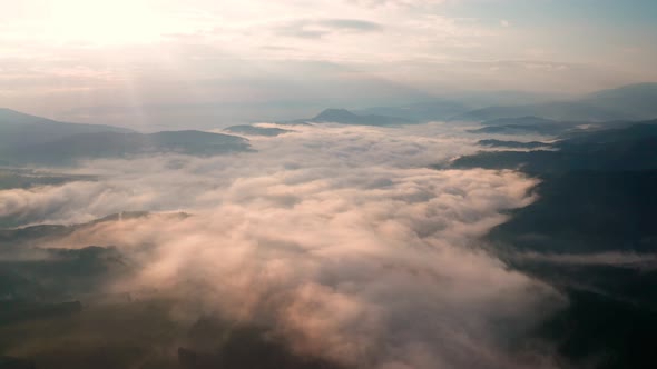 Low clouds and morning mists over mountain slopes at sunrise