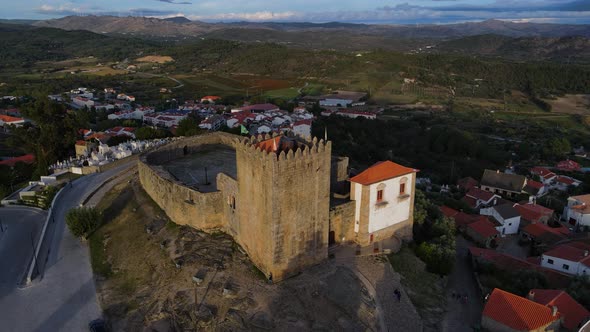 A drone captures a flock of birds flying past the Belmonte Castle tower as the sunsets.