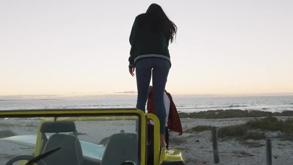 Happy caucasian couple getting out of beach buggy by the sea