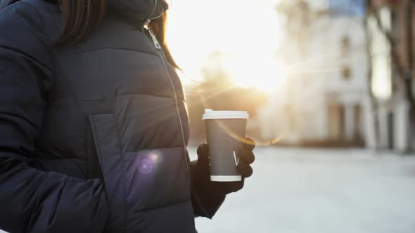 Close Up of the Girl's Hands in Gloves Drinking Coffee, Sunny Winter, Lens Flare From the Sun