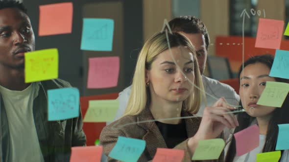 Business Woman Draws a Graph on Glass Wall with Stickers