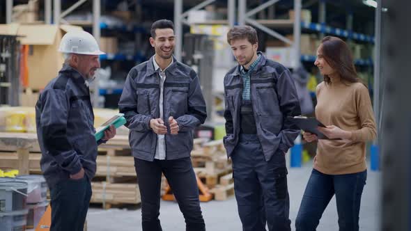 Cheerful Laughing Warehouse Employees Talking on Break in Storehouse Indoors