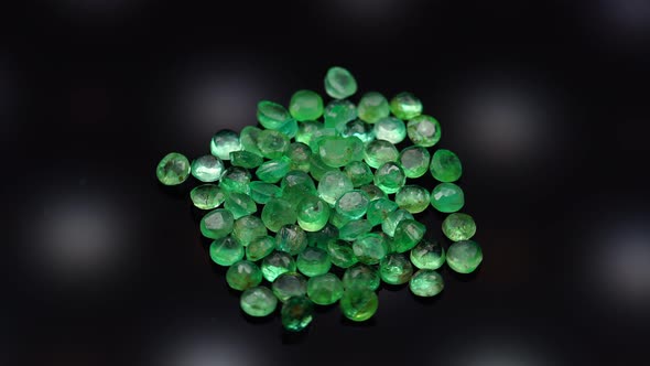 Natural Green Emerald on the Turning Table on the Black Background