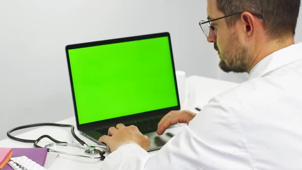 Senior Doctor Working on Chroma Key Laptop in Medical Clothes