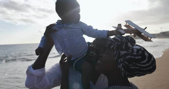 African parents and cute little son having fun on the beach at sunset