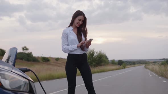 Woman Stands on the Road and Looks in Her White Phone