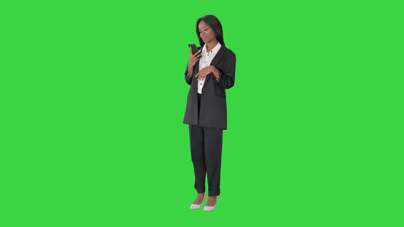 Smiling Black Woman Texting on Her Cell Phone on a Green Screen, Chroma Key.