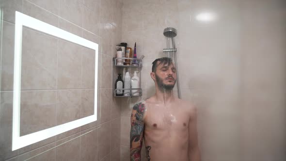 Handsome Young Man Relaxing Under Shower with Closed Eyes