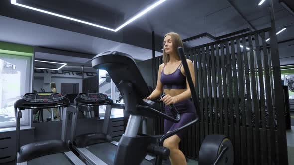 Athletic Caucasian Woman Training Body Muscle on Elliptical Walking Machine